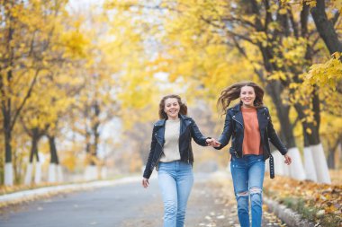 Genç güzel kızları sonbahar arka planda açık havada eğleniyor. Sonbahar zaman neşeli arkadaşlar