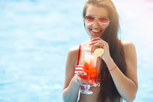 Very beautiful young woman with cocktail in the swimming pool