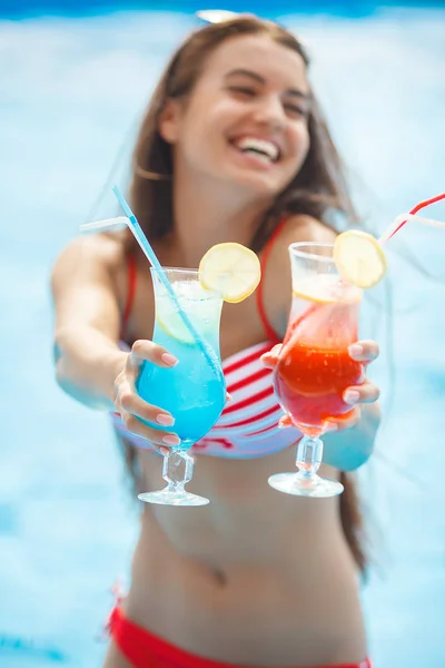 Very beautiful young woman with cocktails in the swimming pool