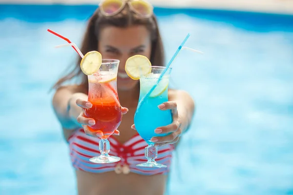 Very beautiful young woman with cocktails in the swimming pool