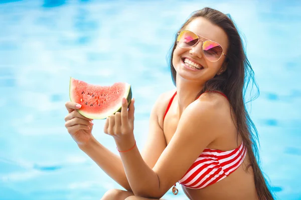 Very beautiful woman with watermelon in the pool