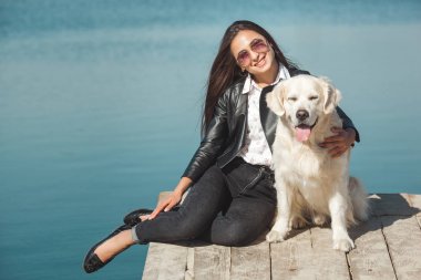 Genç çekici kadın köpeğiyle iskelede oturuyordu. En iyi arkadaşlar açık havada