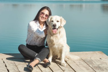 Genç çekici kadın köpeğiyle iskelede oturuyordu. En iyi arkadaşlar açık havada