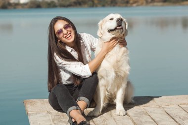 Genç çekici kadın köpeğiyle iskelede oturuyordu. En iyi arkadaşlar açık havada