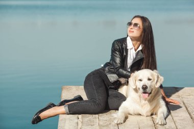 Genç çekici kadın köpeğiyle iskelede oturuyordu. En iyi arkadaşlar açık havada