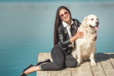 Genç çekici kadın köpeğiyle iskelede oturuyordu. En iyi arkadaşlar açık havada