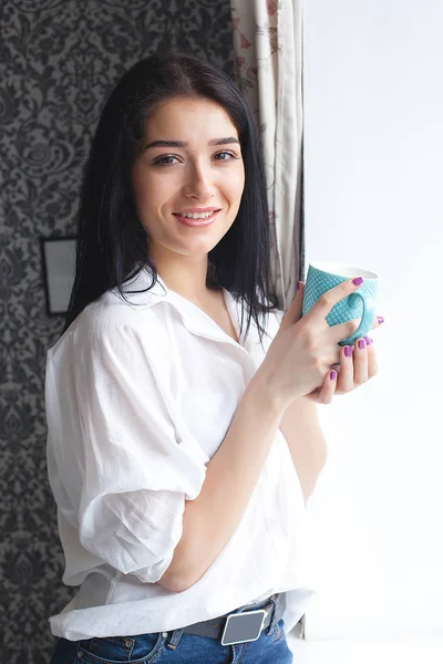 Genç çekici kadın mutfağını çay veya kahve içme. Bayan kapalı sıcak içecek bir bardak ile rahatlatıcı