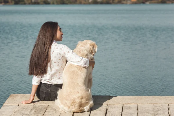 Genç çekici kadın köpeğiyle iskelede oturuyordu. En iyi arkadaşlar açık havada
