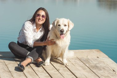 Genç çekici kadın köpeğiyle iskelede oturuyordu. En iyi arkadaşlar açık havada