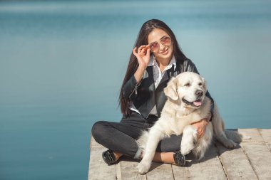 Genç çekici kadın köpeğiyle iskelede oturuyordu. En iyi arkadaşlar açık havada