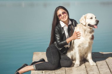 Genç çekici kadın köpeğiyle iskelede oturuyordu. En iyi arkadaşlar açık havada