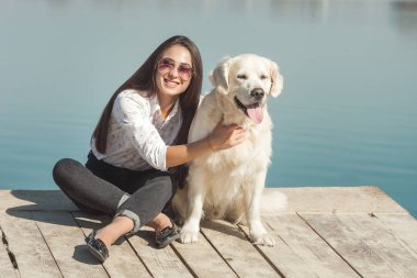 Genç çekici kadın köpeğiyle iskelede oturuyordu. En iyi arkadaşlar açık havada