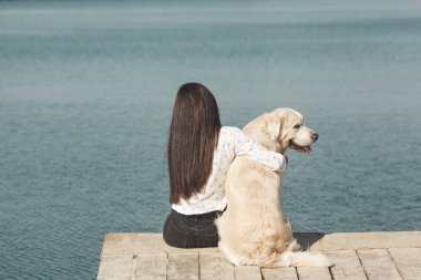 Genç çekici kadın köpeğiyle iskelede oturuyordu. En iyi arkadaşlar açık havada
