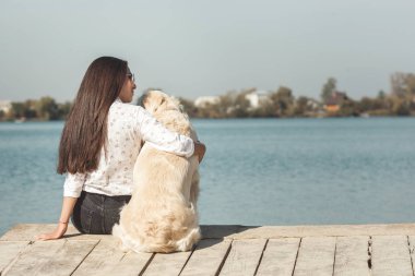 Genç çekici kadın köpeğiyle iskelede oturuyordu. En iyi arkadaşlar açık havada