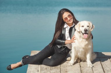 Genç çekici kadın köpeğiyle iskelede oturuyordu. En iyi arkadaşlar açık havada