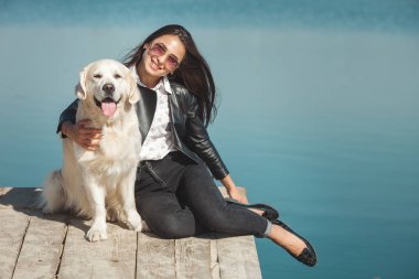Genç çekici kadın köpeğiyle iskelede oturuyordu. En iyi arkadaşlar açık havada