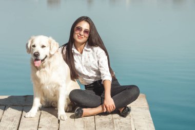 Genç çekici kadın köpeğiyle iskelede oturuyordu. En iyi arkadaşlar açık havada