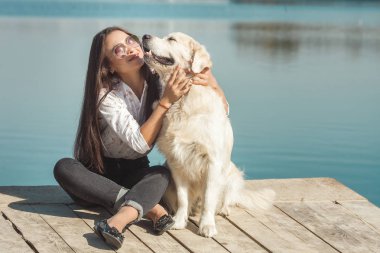 Genç çekici kadın köpeğiyle iskelede oturuyordu. En iyi arkadaşlar açık havada
