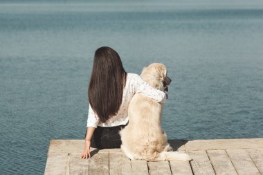Genç çekici kadın köpeğiyle iskelede oturuyordu. En iyi arkadaşlar açık havada