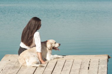 Genç çekici kadın köpeğiyle iskelede oturuyordu. En iyi arkadaşlar açık havada