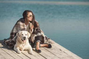 Genç çekici kadın köpeğiyle iskelede oturuyordu. En iyi arkadaşlar açık havada