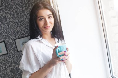 Genç çekici kadın mutfağını çay veya kahve içme. Bayan kapalı sıcak içecek bir bardak ile rahatlatıcı