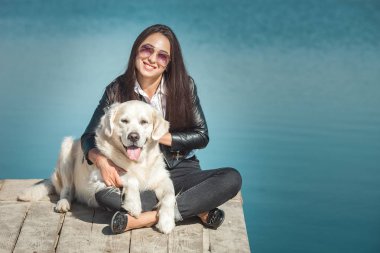 Genç çekici kadın köpeğiyle iskelede oturuyordu. En iyi arkadaşlar açık havada