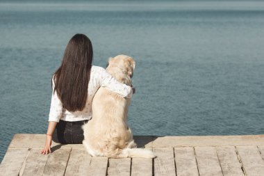 Genç çekici kadın köpeğiyle iskelede oturuyordu. En iyi arkadaşlar açık havada