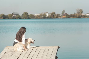 Genç çekici kadın köpeğiyle iskelede oturuyordu. En iyi arkadaşlar açık havada