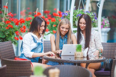 Grup Genç neşeli kadınların laptop arıyorum ve açık havada online alışveriş yapma