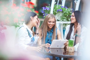 Grup Genç neşeli kadınların tablet vasıl seyir ve açık havada online alışveriş yapma
