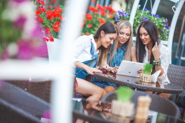 Grup Genç neşeli kadınların tablet vasıl seyir ve açık havada online alışveriş yapma