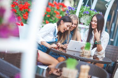 Grup Genç neşeli kadınların tablet vasıl seyir ve açık havada online alışveriş yapma