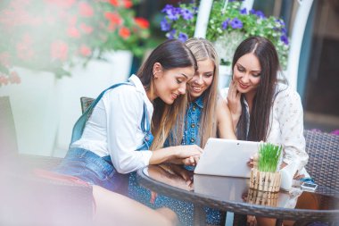 Grup Genç neşeli kadınların tablet vasıl seyir ve açık havada online alışveriş yapma