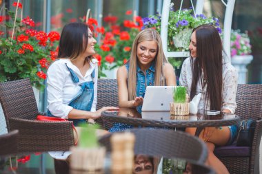 Grup Genç neşeli kadınların tablet vasıl seyir ve açık havada online alışveriş yapma