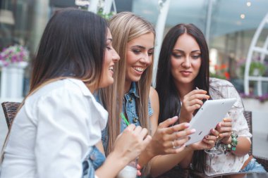 Grup Genç neşeli kadınların tablet vasıl seyir ve açık havada online alışveriş yapma