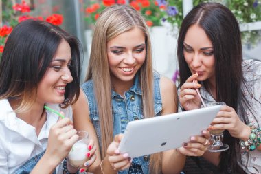 Grup Genç neşeli kadınların tablet vasıl seyir ve açık havada online alışveriş yapma