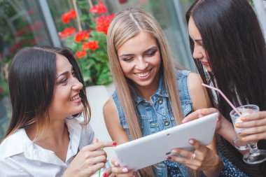 Grup Genç neşeli kadınların tablet vasıl seyir ve açık havada online alışveriş yapma