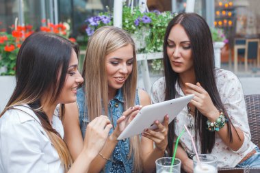 Grup Genç neşeli kadınların tablet vasıl seyir ve açık havada online alışveriş yapma