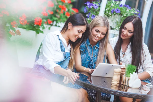 Grup Genç neşeli kadınların tablet vasıl seyir ve açık havada online alışveriş yapma