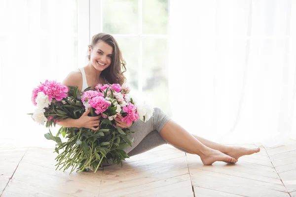 Young attractive woman with pink and white peony flowers