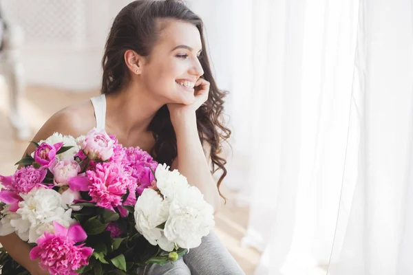 Young attractive woman with pink and white peony flowers