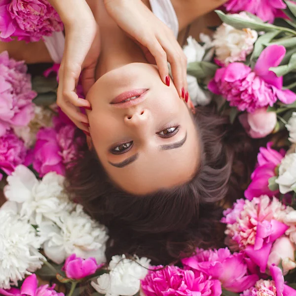 Young attractive woman with pink and white peony flowers