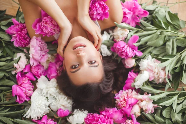 Young attractive woman with pink and white peony flowers