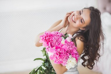 Pembe ve beyaz şakayık çiçekleri olan çekici kadın