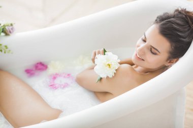 Genç güzel kadın alarak banyo çiçek ve süt ile