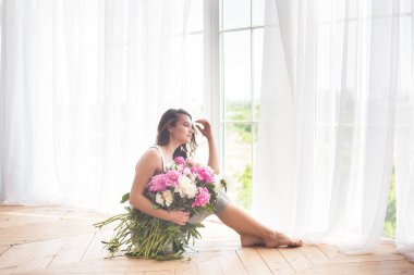 Pembe ve beyaz şakayık çiçekleri olan çekici kadın