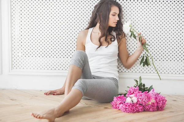 Young attractive woman with pink and white peony flowers