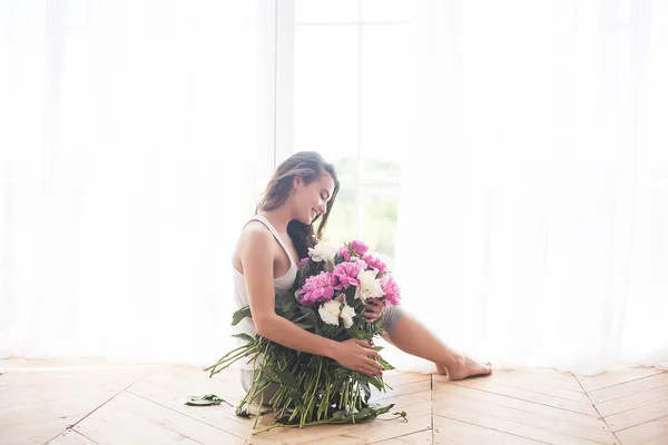 Young attractive woman with pink and white peony flowers