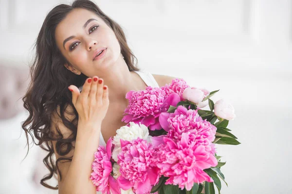 Young attractive woman with pink and white peony flowers